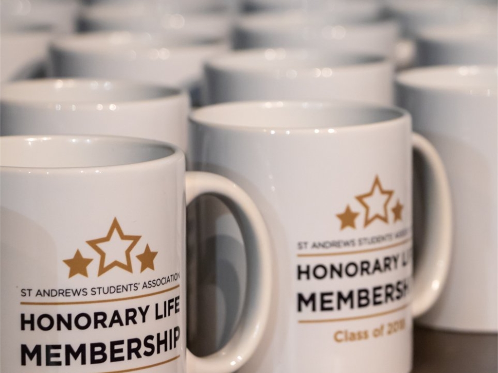 White mugs with the Honorary Life Membership logo on them.