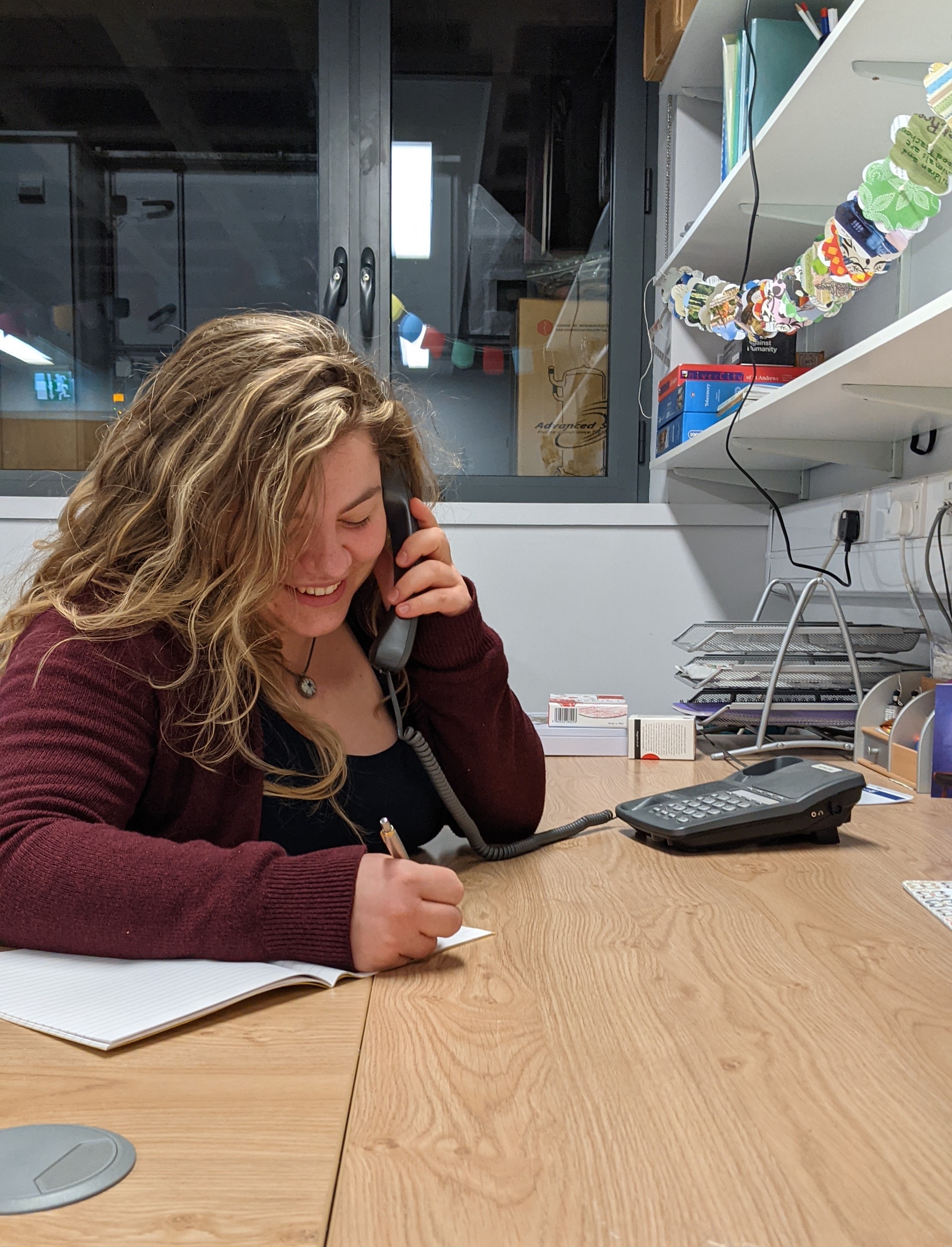 A member of staff on the phone and taking notes.