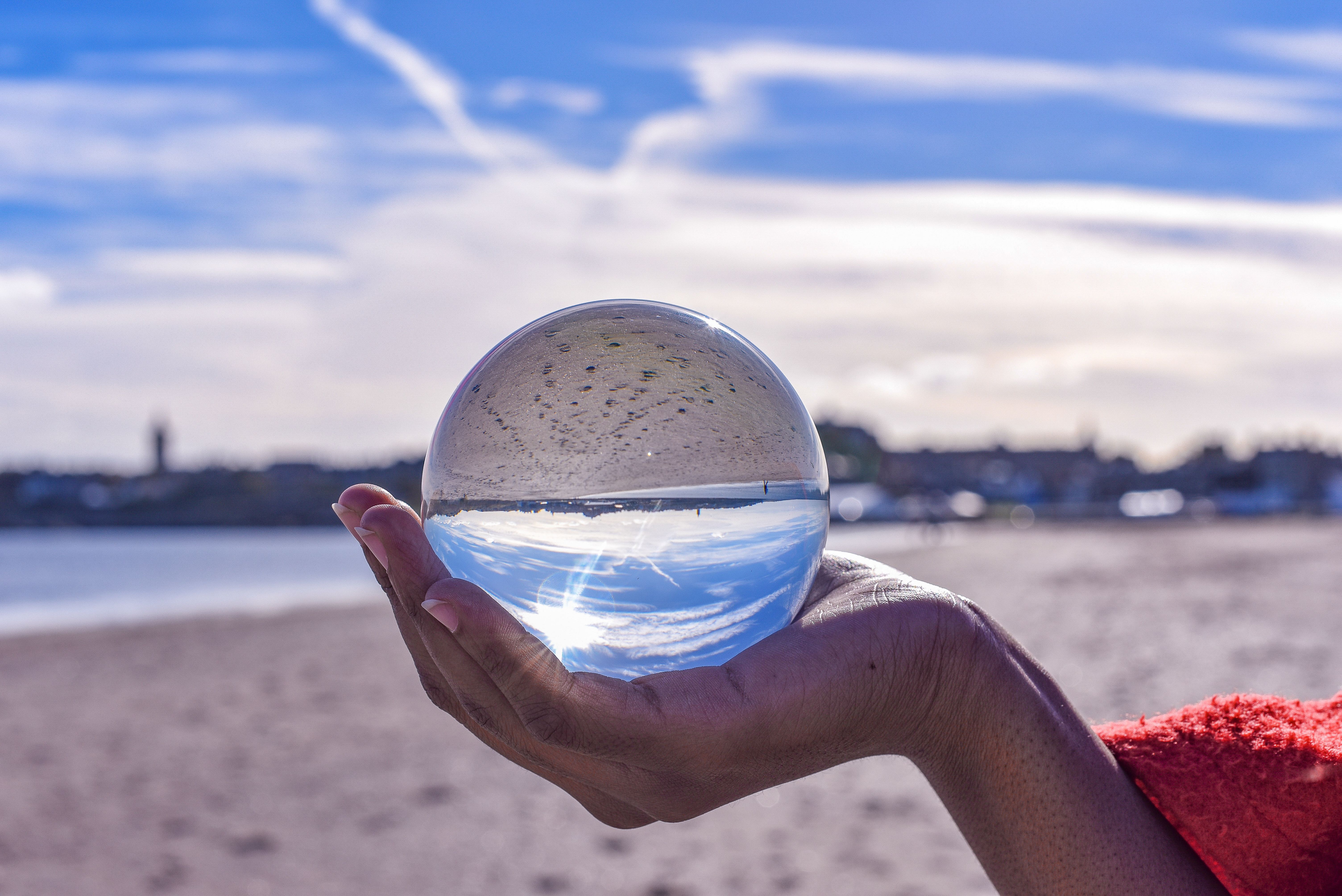 Hand holding a spherical glass ball in front of the town on West Sands.