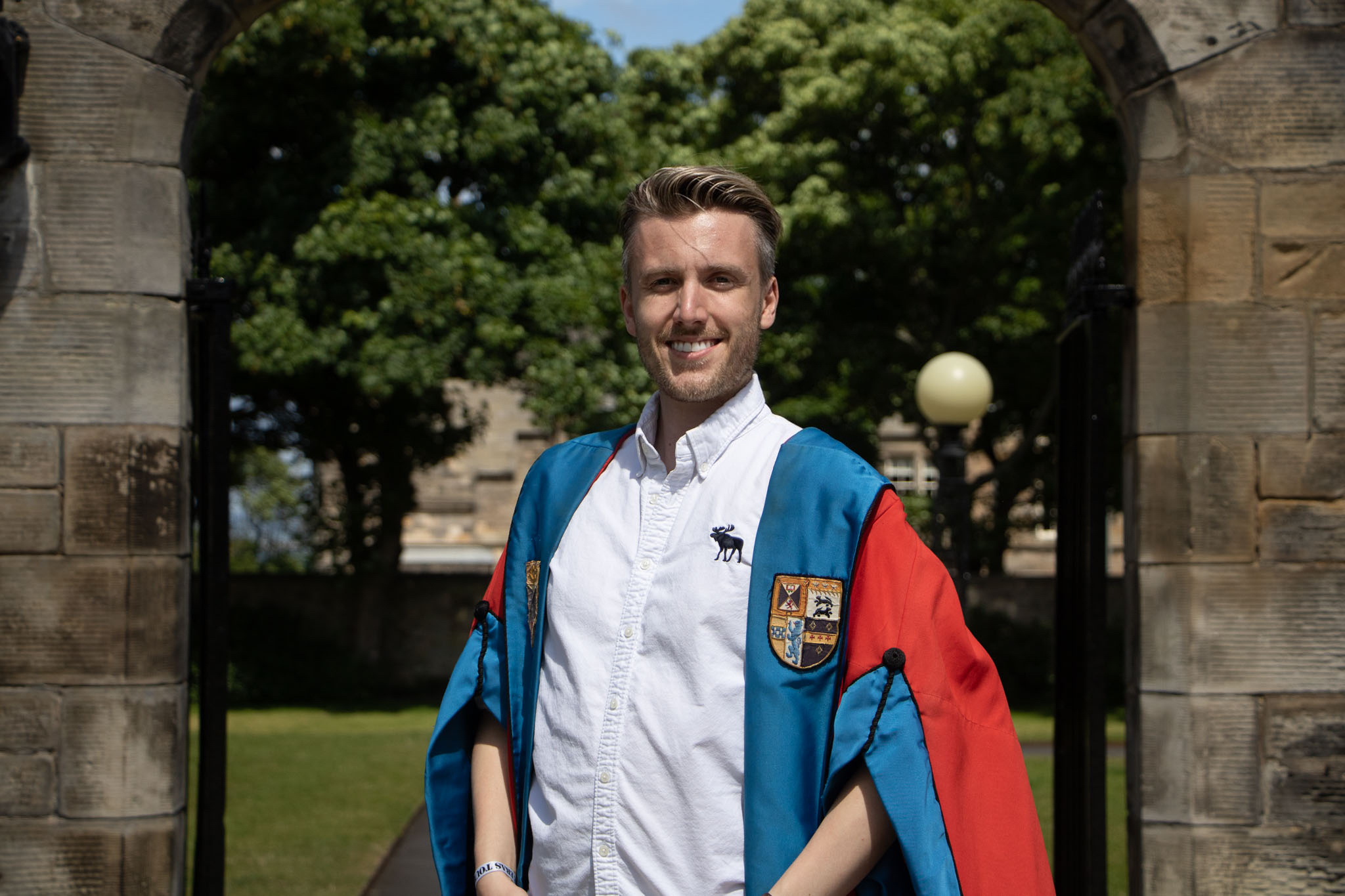 Cam smiles in his President's red gown. The gown is faced blue with the Association crest emblazoned.
