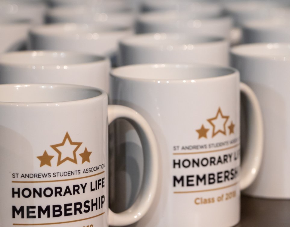 White mugs with the Honorary Life Membership logo on them.