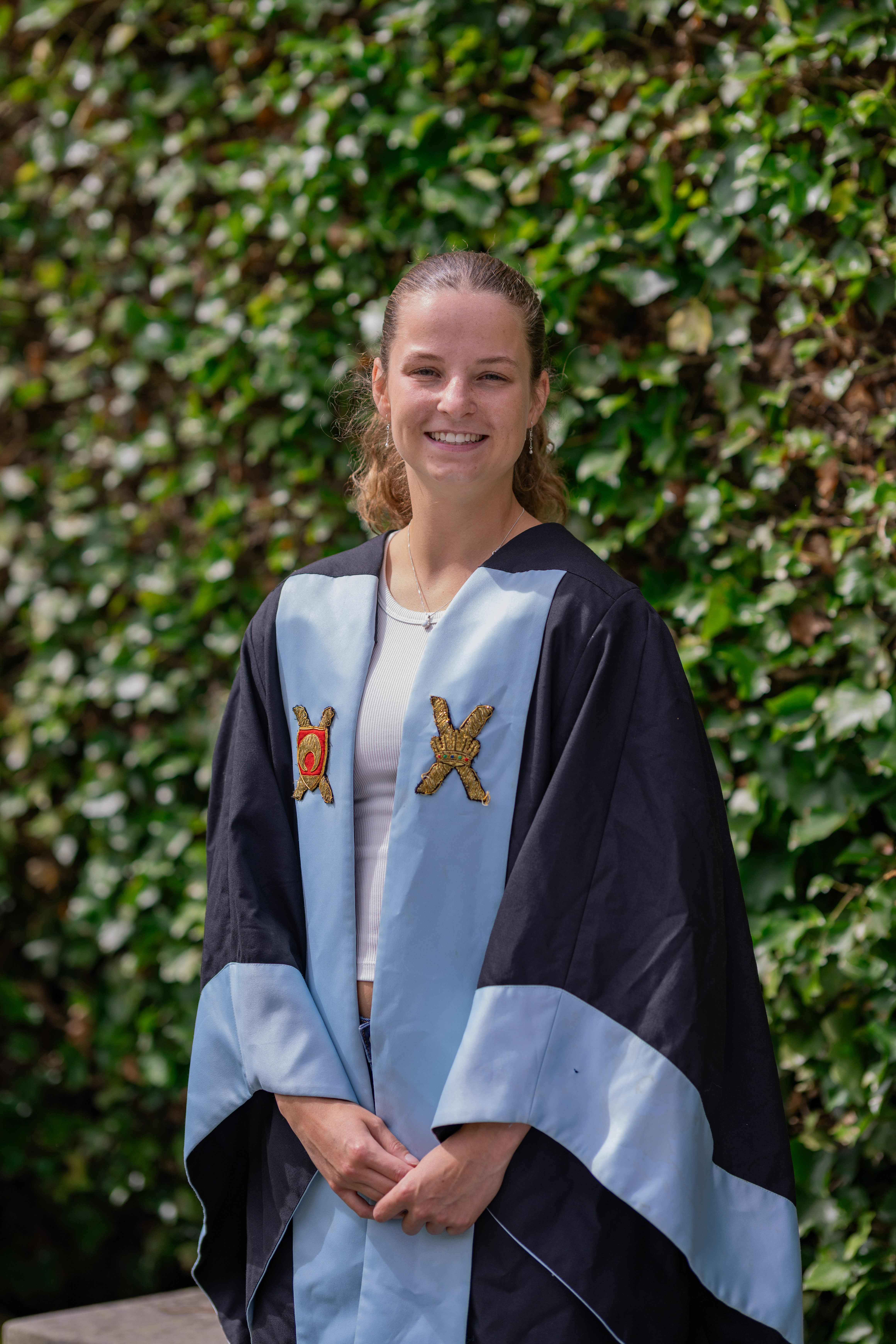 Amy smiles in the Athletic Association gown. The gown is faced and lined in azure with the Full Blue and Half Blue crests emblazoned.