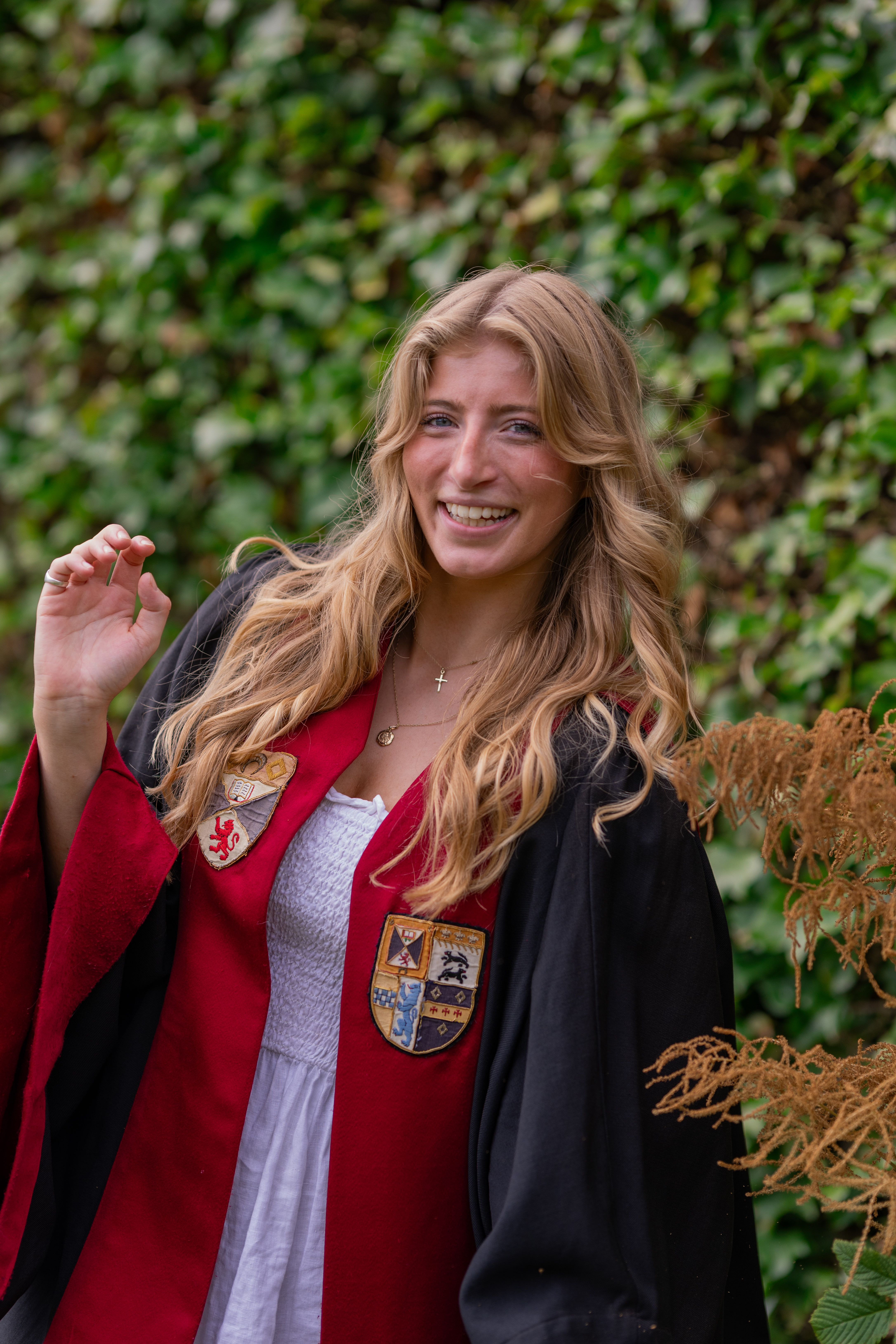 Alice Hodges smiles in the President of Union Affairs gown. The gown is faced gold with the Association and University crests emblazoned.