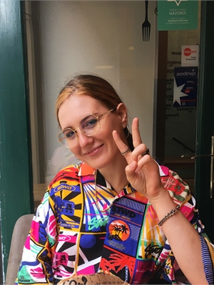 Rache sitting in a colorful shirt showing a peace sign