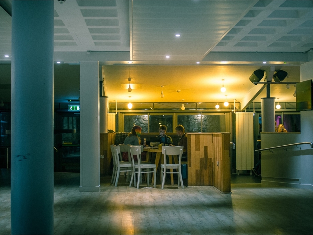 Three students sit in Main Bar, dimly lit.