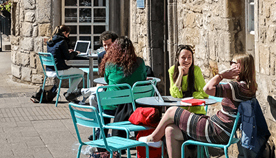 People sit outside Old Union Coffee Shop, chatting around tables and drinking coffee.