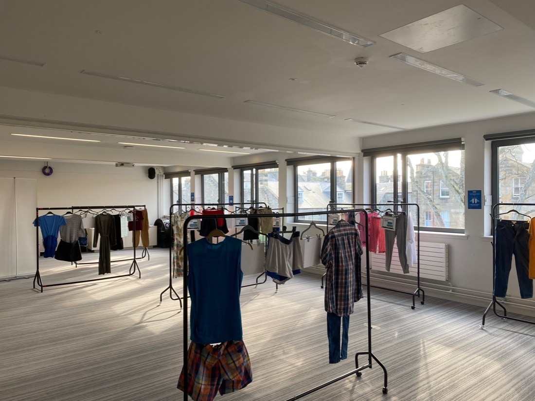 Items of clothing arranged as outfits on hangers on clothing rails.