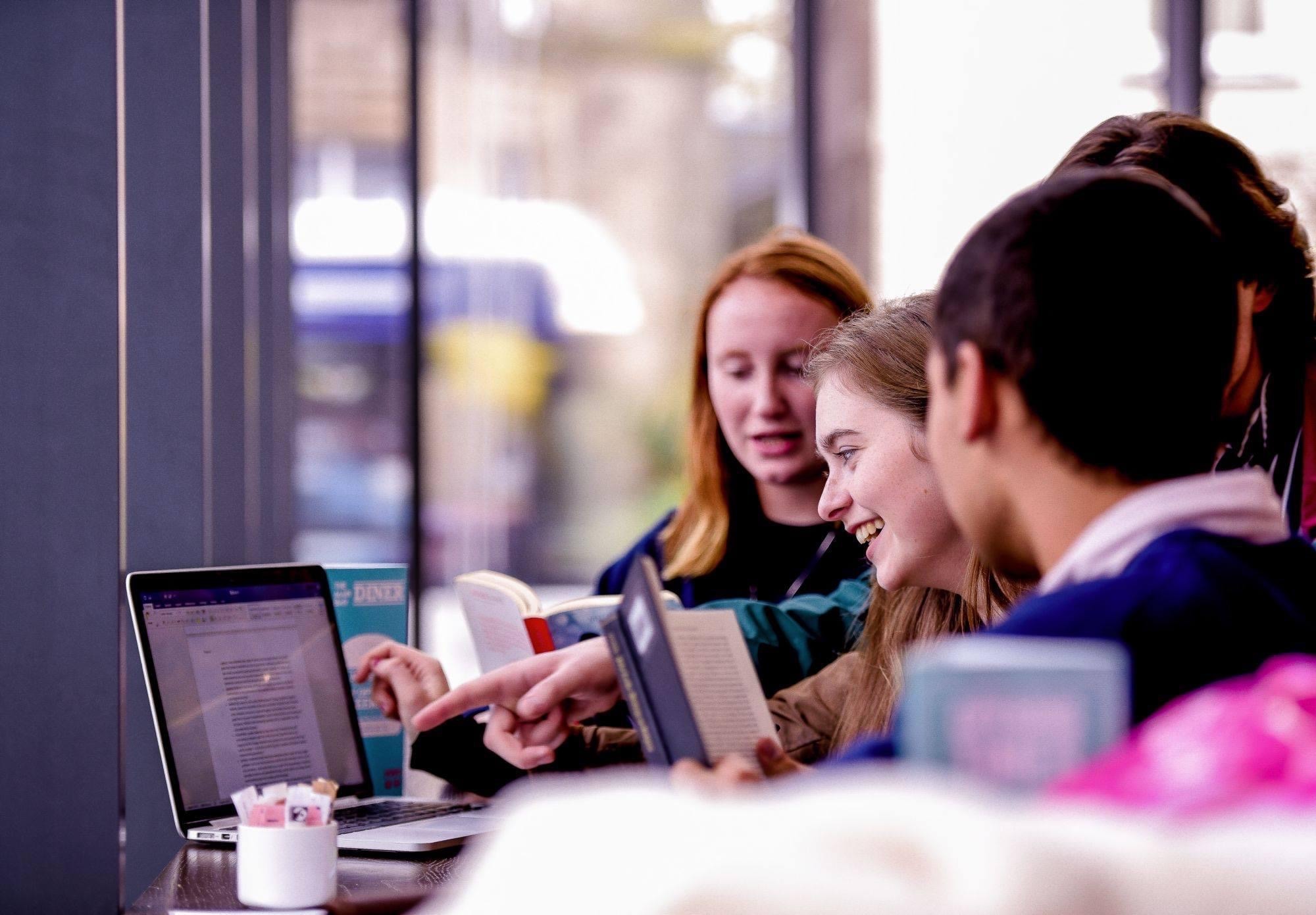Students working together on laptops by the window in Rector's Cafe